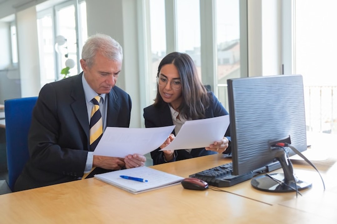 Profesional explicando detalles de documentos a un cliente en el trabajo
