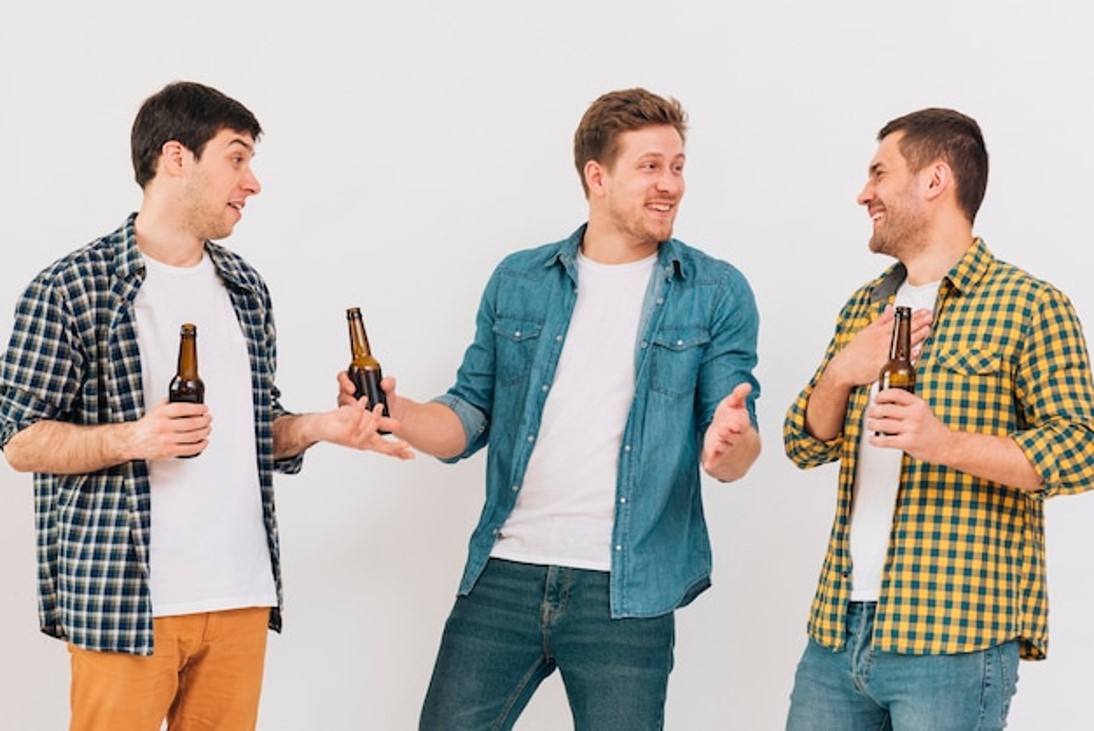 Amigos jóvenes felices sosteniendo una botella de cerveza en la mano y burlándose